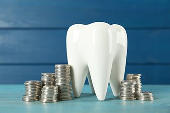 A model tooth surrounded by coins 