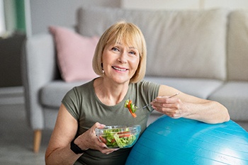 Mature woman eating salad with help of dental implants in Plano
