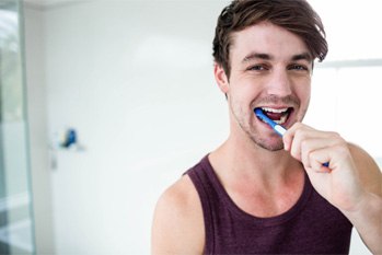 man brushing teeth for dental implant care in Plano