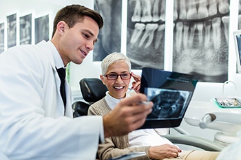 Dentist and smiling patient looking at X-ray