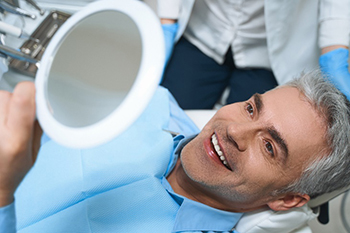 Closeup of mature man in dental chair smiling with veneers