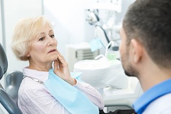 senior woman with mouth pain talking to her emergency dentist in Plano 