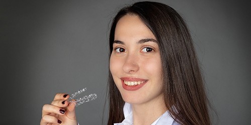 A young woman preparing to insert an Invisalign aligner into her mouth
