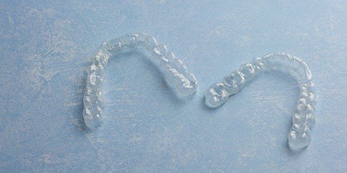 A set of clear Invisalign aligners sitting next to each other