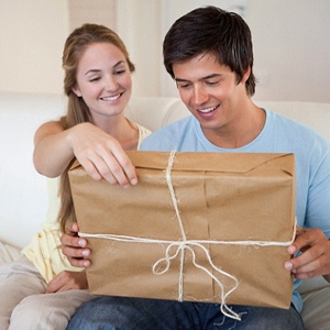Happy couple sitting on couch, looking at package