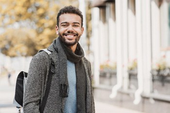 Man with backpack smiling while walking outside