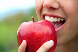 close up of person eating red apple to boost immune system 