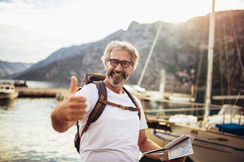 mature man smiling with dental implants and giving thumbs up
